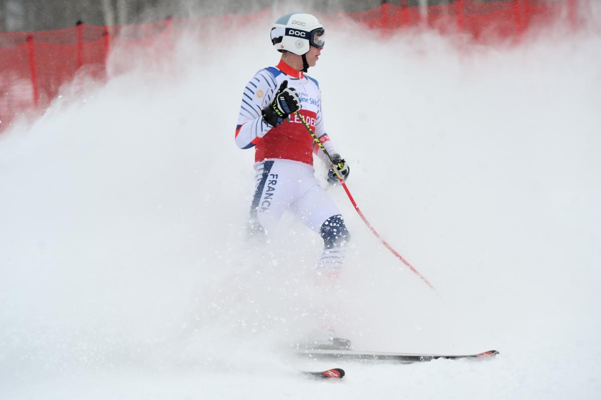 A male skier with a wave of snow behind him