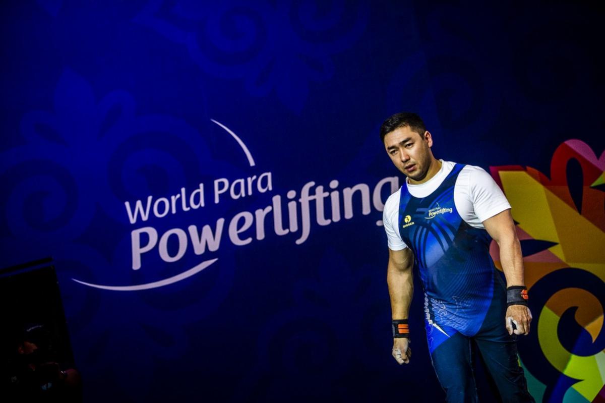 An athlete walking in front of a banner written World Para Powerlifting