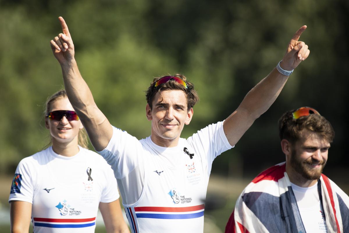 Male British rower smiles with both arms raised