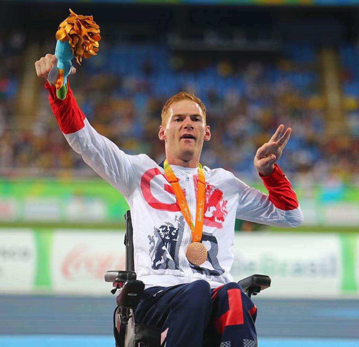 Male British athlete with cerebral palsy celebrates on the podium