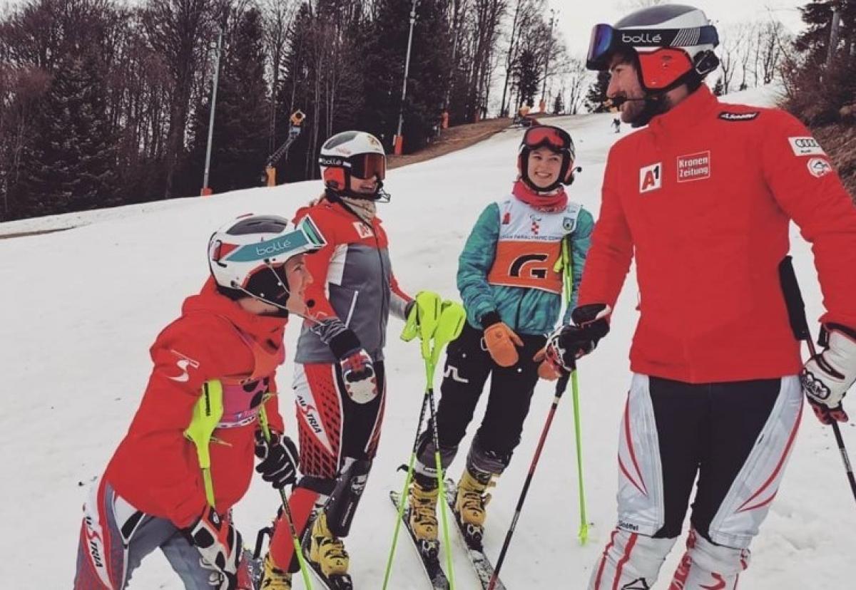 A group of three female and one male skier talking on a ski slope