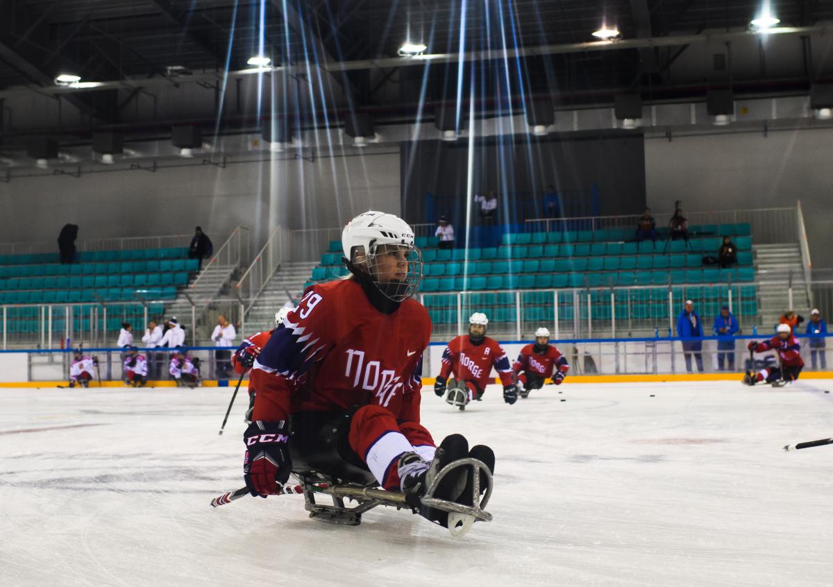 A female Para ice hockey player practising with her teammates on a rink