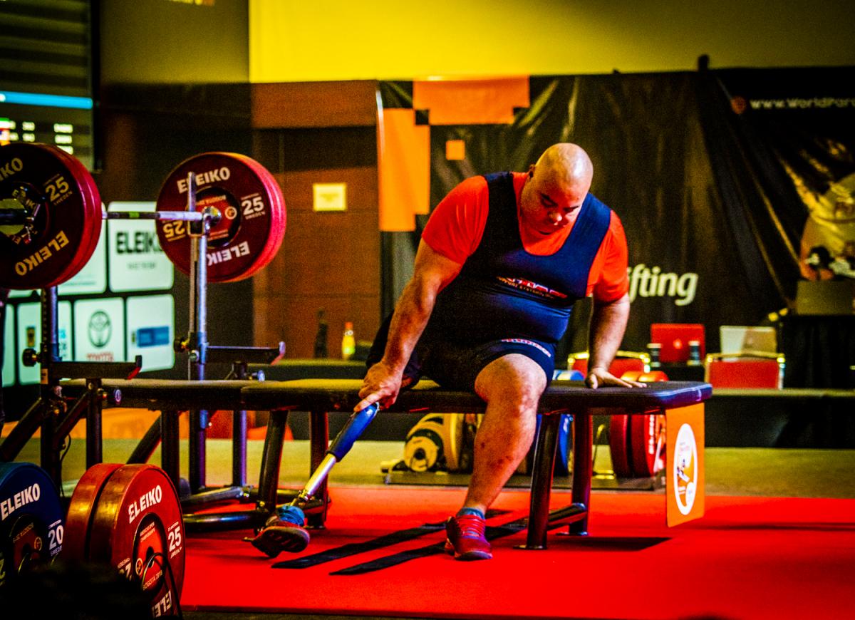 A man on a bench press in a Para powerlifting competition