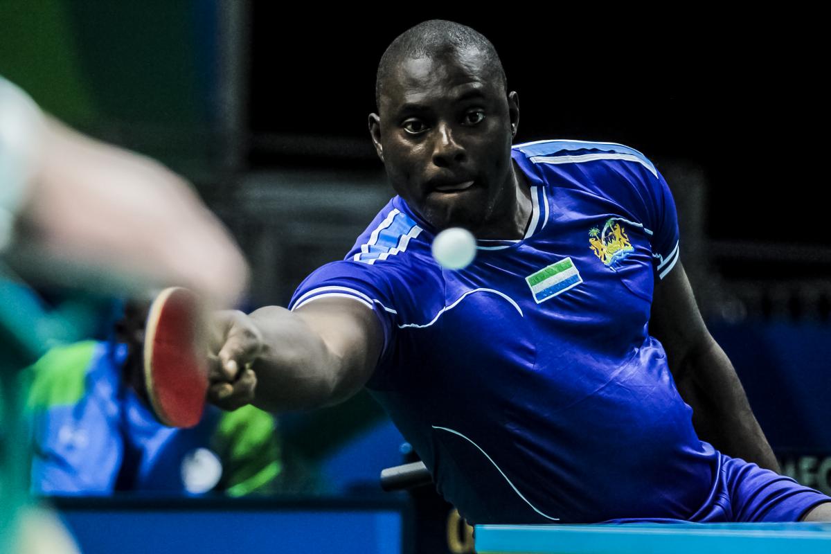 African table tennis player reaches for a shot
