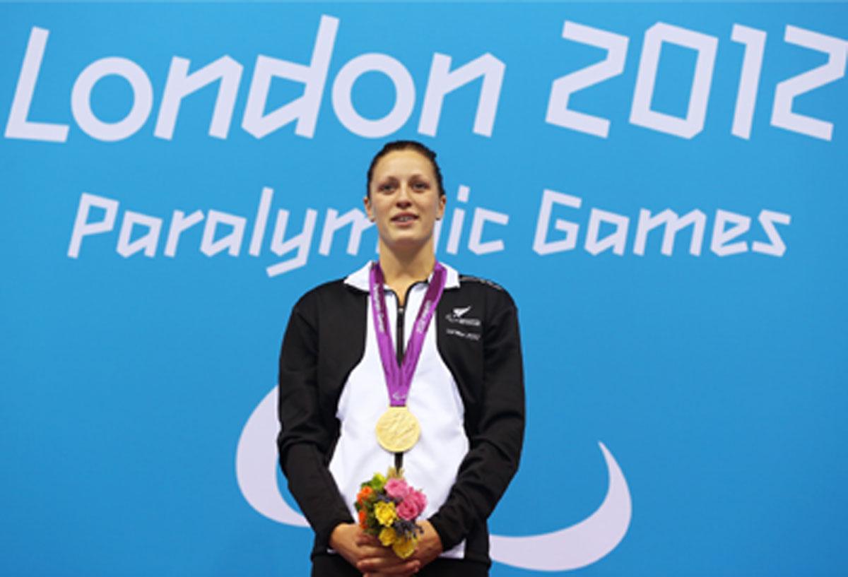 A picture of a woman with a gold medal around her neck during a medal ceremony