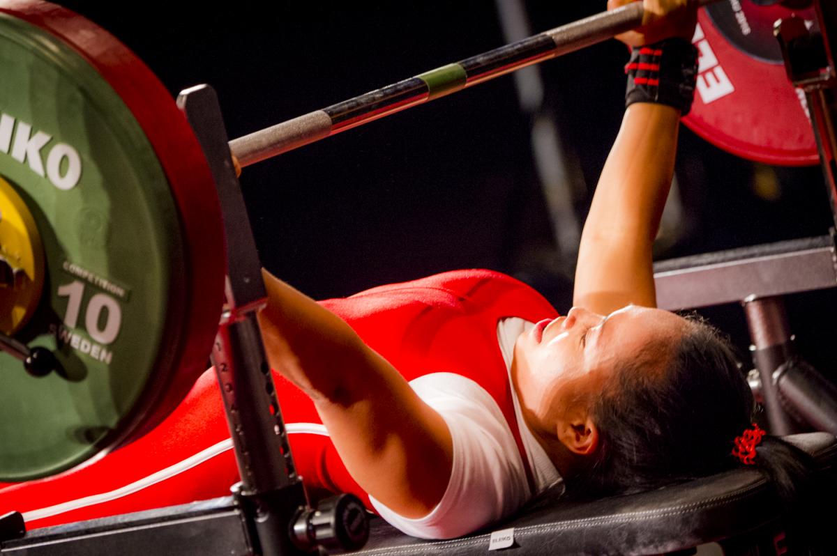 A woman preparing to lift a bar on a bench press 