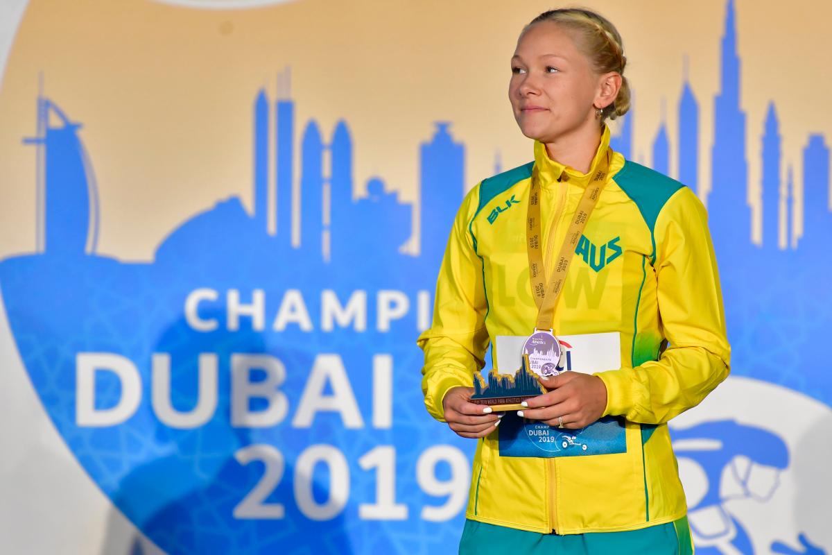 A woman with a medal standing on a stage
