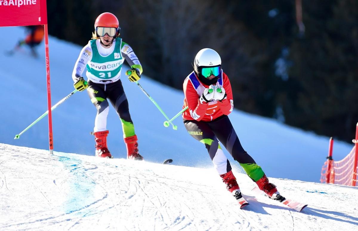 A female guide alpine skier ahead of a male Para alpine skier on a slope