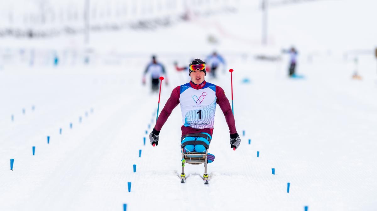 A man in a sit-ski competing in a  Para cross-country race