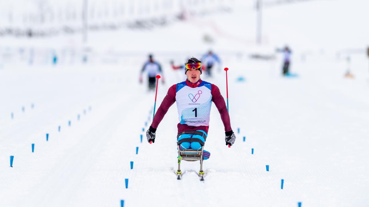 A man in a sit-ski competing in a Para cross-country race