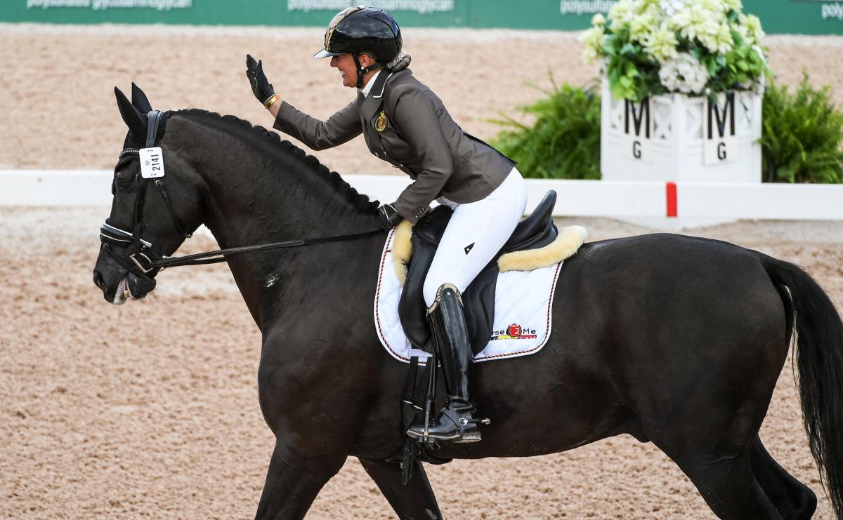 Woman riding horse and patting it on the head