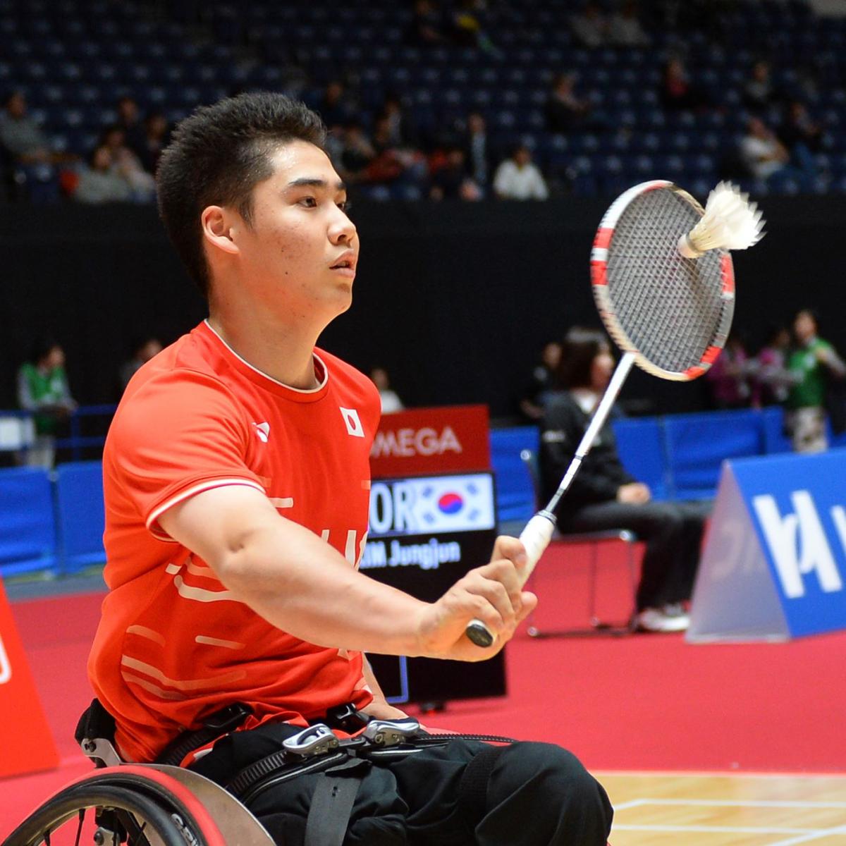 Japanese male badminton player in wheelchair hits a return