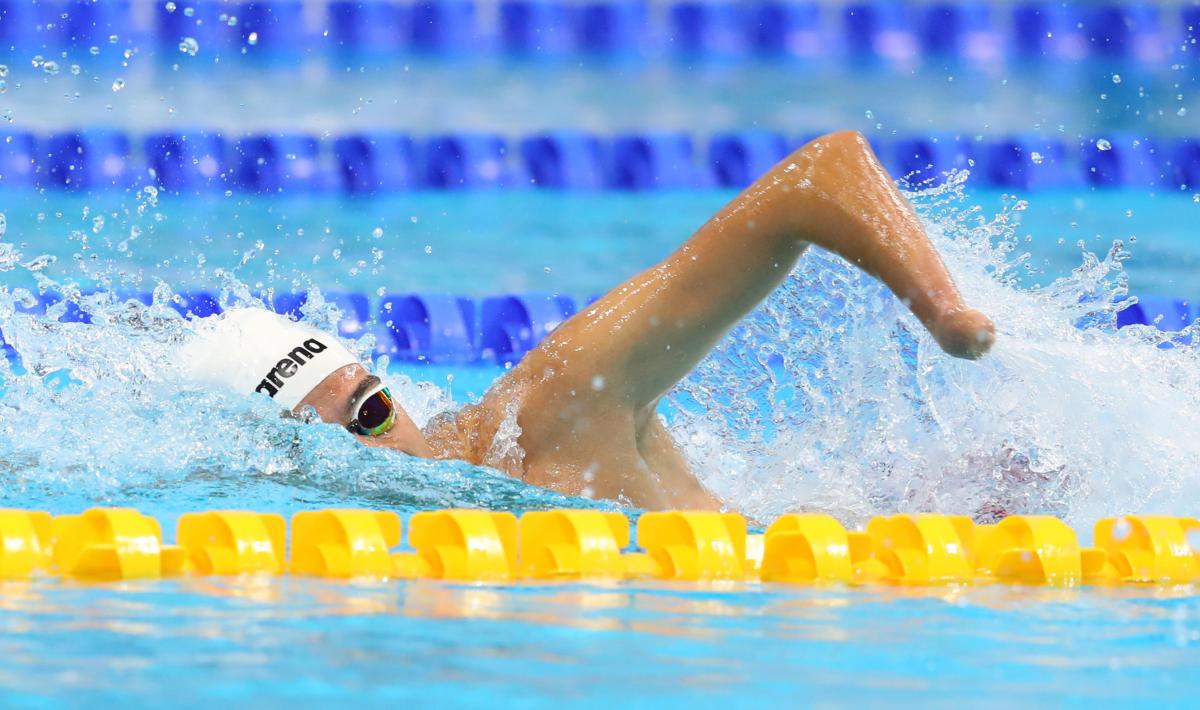 A male swimmer without his left hand swimming a pool
