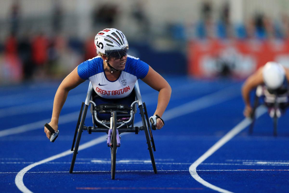 A female wheelchair racer crossing the line on a blue track