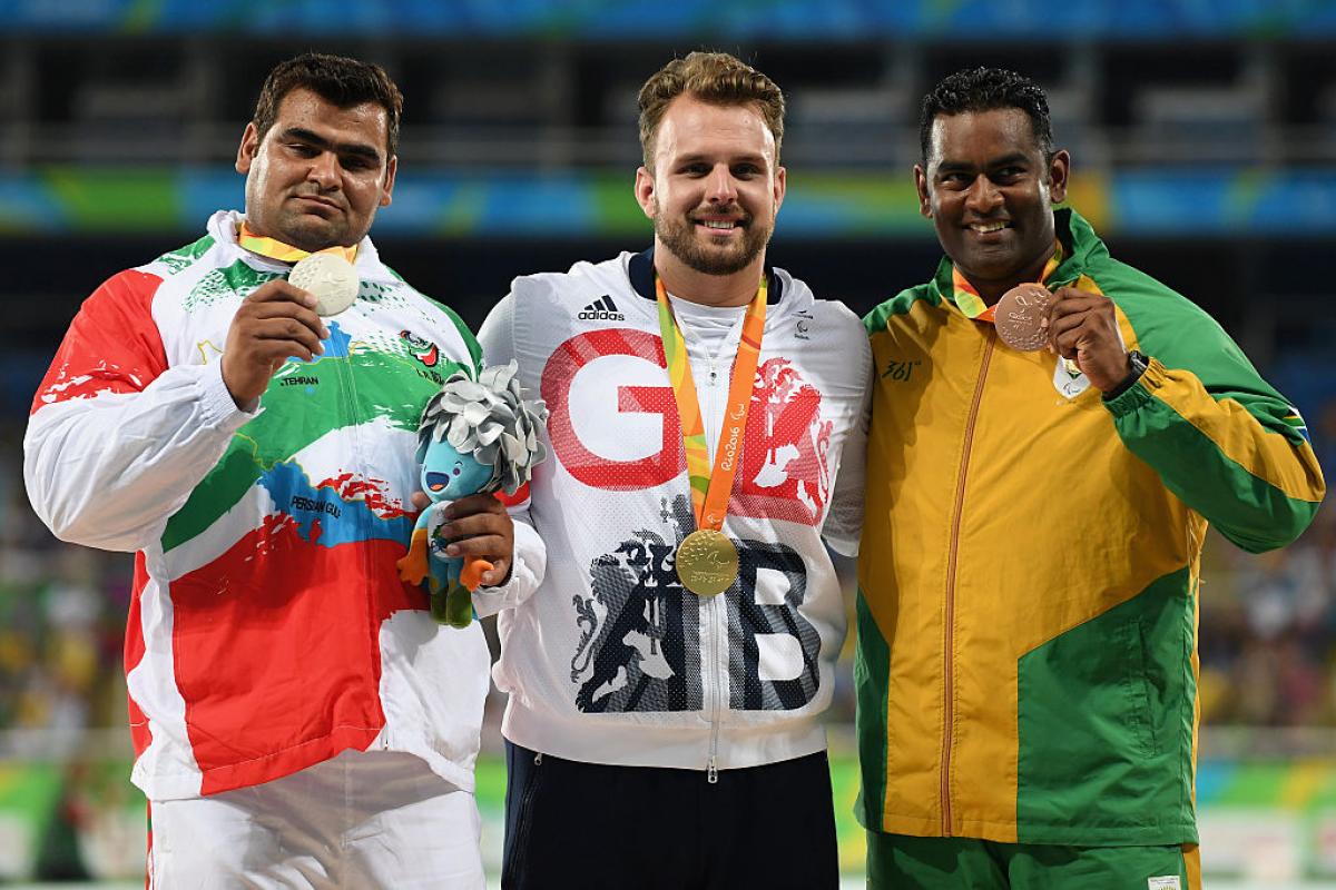 Three men who compete in shot put pose with their medals