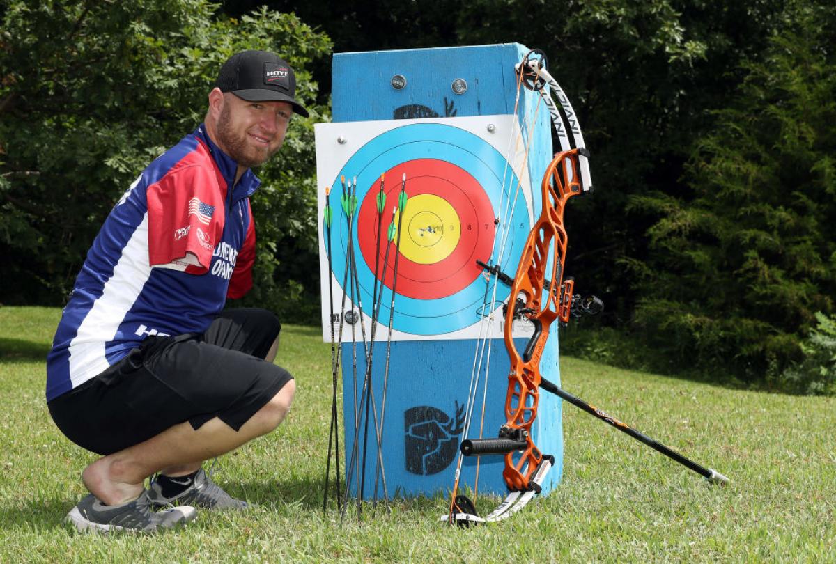 Male archer without arms poses next to his targets