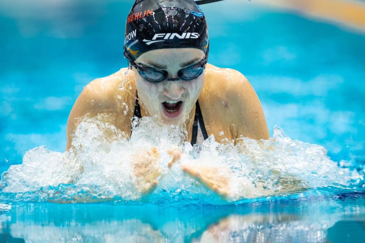 A woman with a black cap swimming breaststroke