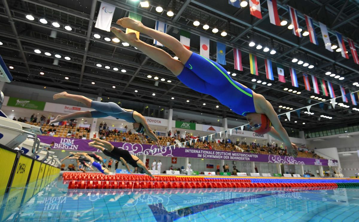 A group of seven female swimmers jumping in the water