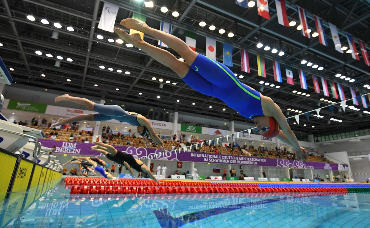 A group of seven female swimmers jumping in the water 