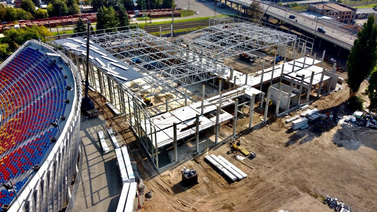 An aerial view of two arenas in construction next to a stadium