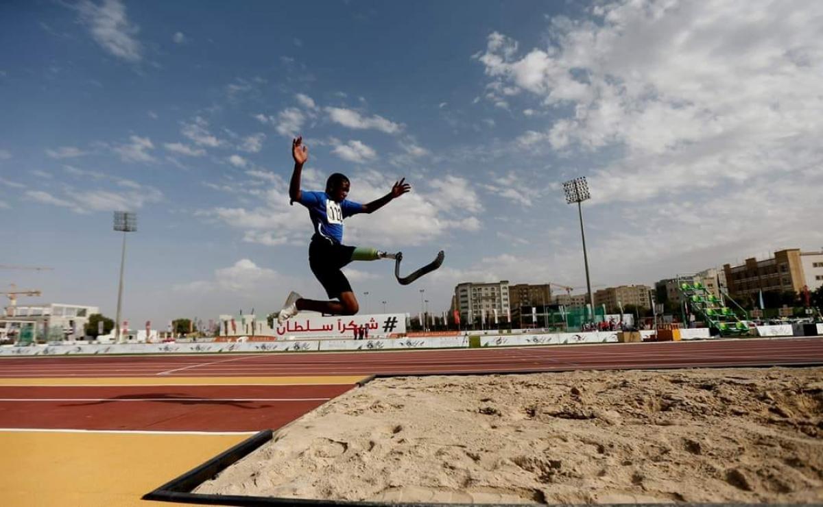 A man with a prosthetic leg jumping in an athletics track