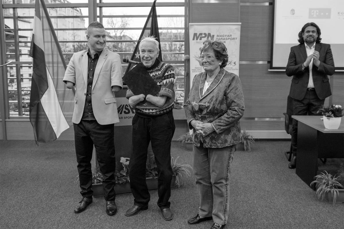 Black and white photo of elderly man without hands receiving an award