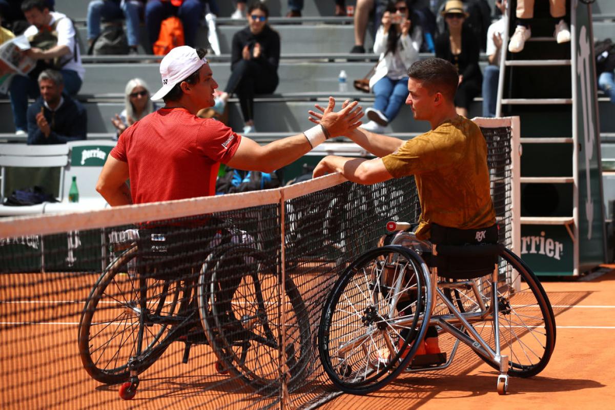 Two male wheelchair tennis players shake hands after a match