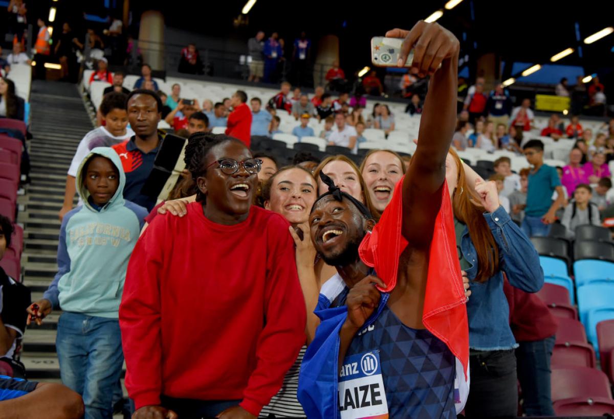 French Black man takes selfie with fans and French flag around him