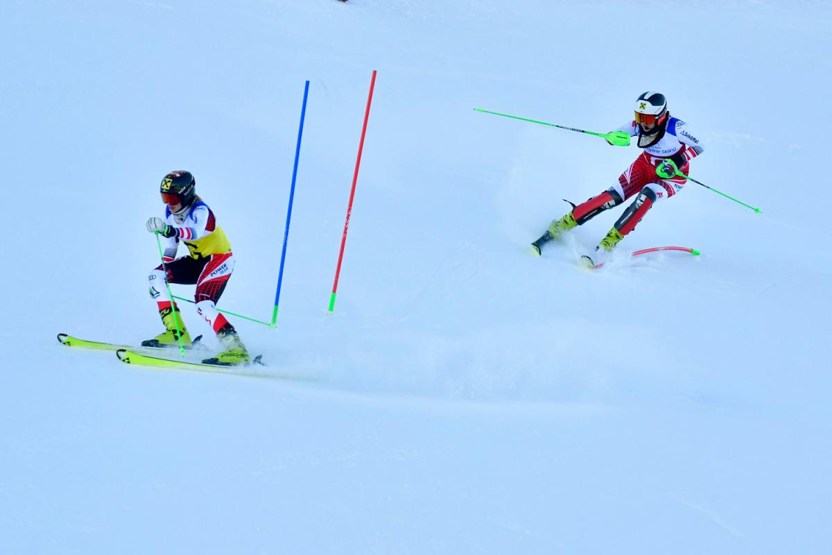 A female Para alpine skier following her guide in a competition in the snow