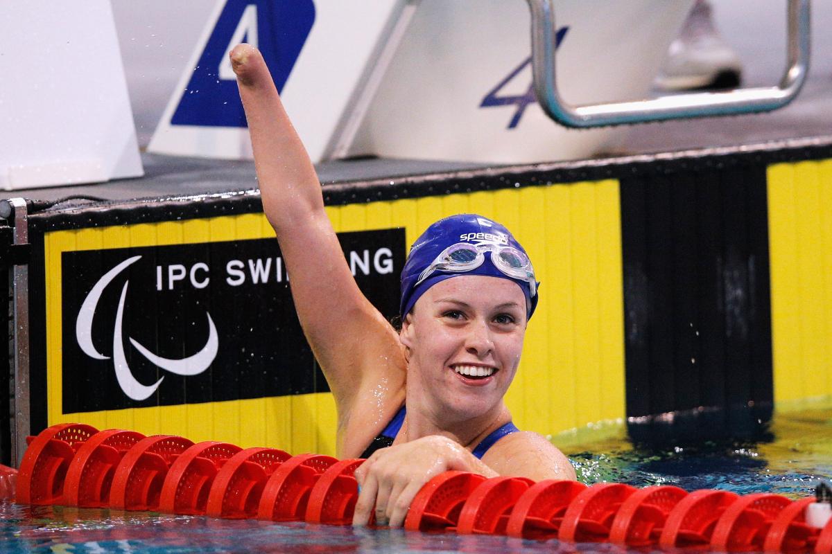 British swimmer Amy Marren lifts her arm and smiles while in the pool after a race