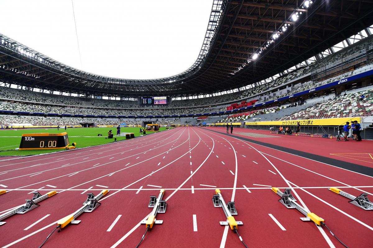 The view of a stadium with a red athletics track seen by the starting line