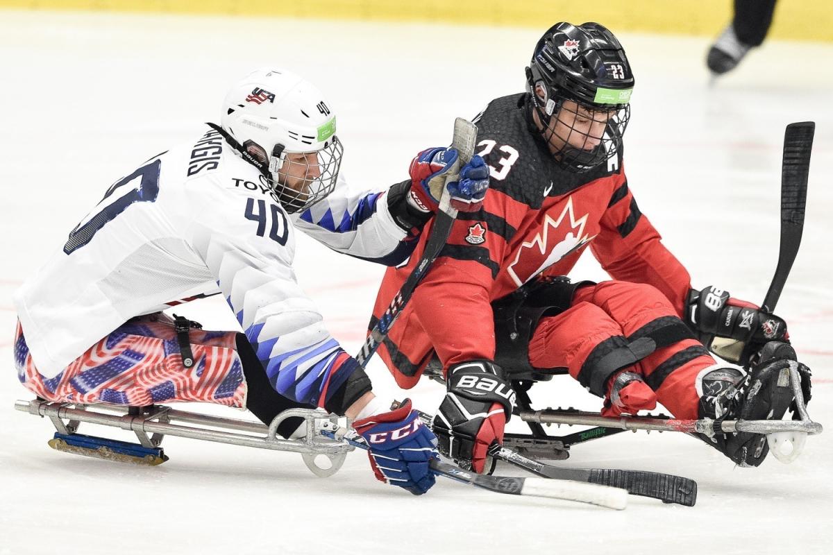 Two men competing in sledges on a Para ice hockey game