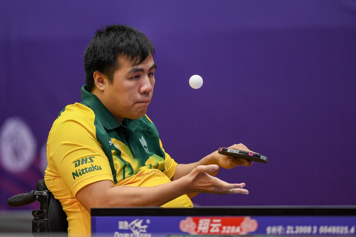 Man in wheelchair serves a table tennis ball