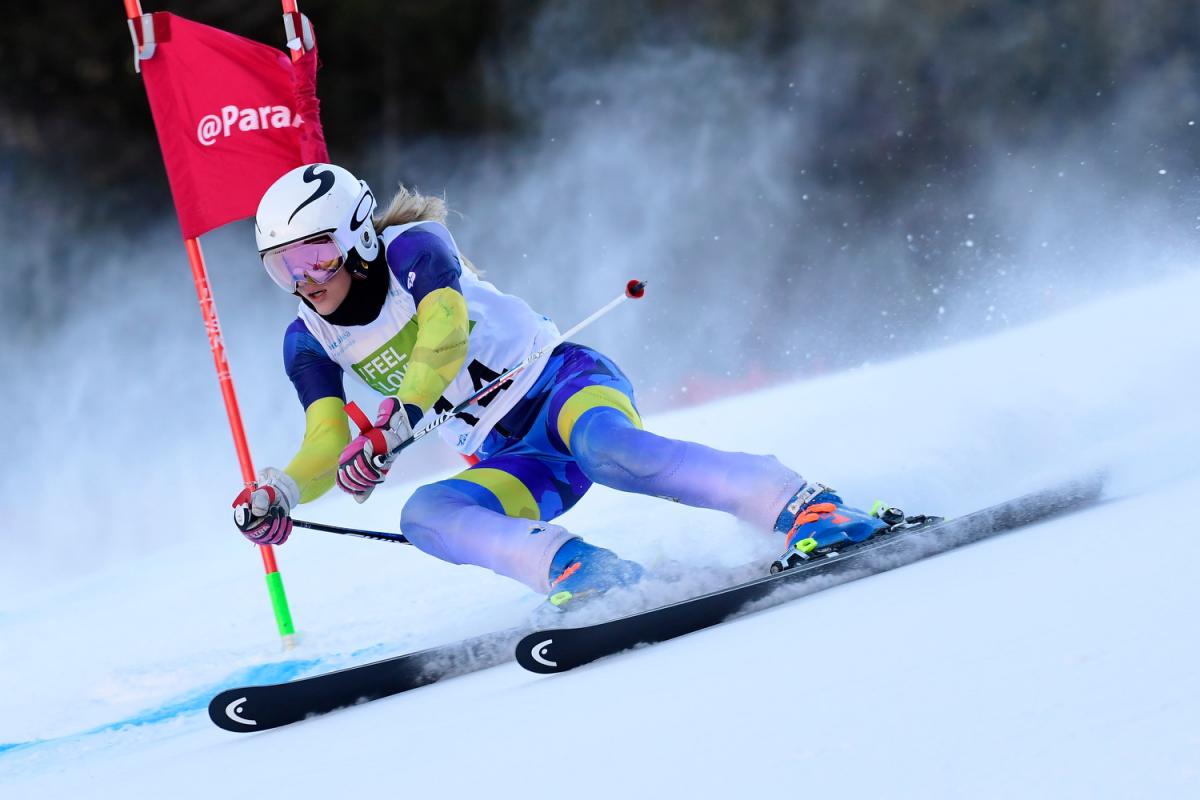 A female Para alpine skier crossing a pole in a slalom event
