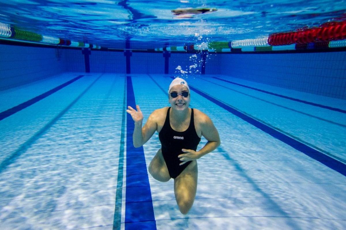 An underwater picture of a female swimmer without legs waving