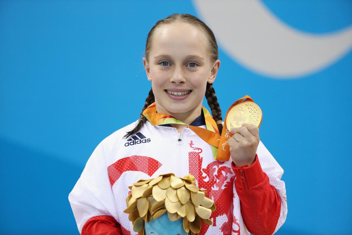 British female swimmer smiling with gold medal