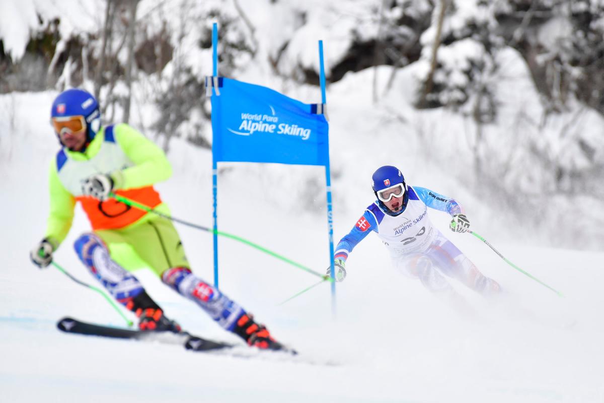 A vision impaired Para alpine skier following the guide in a downhill competition