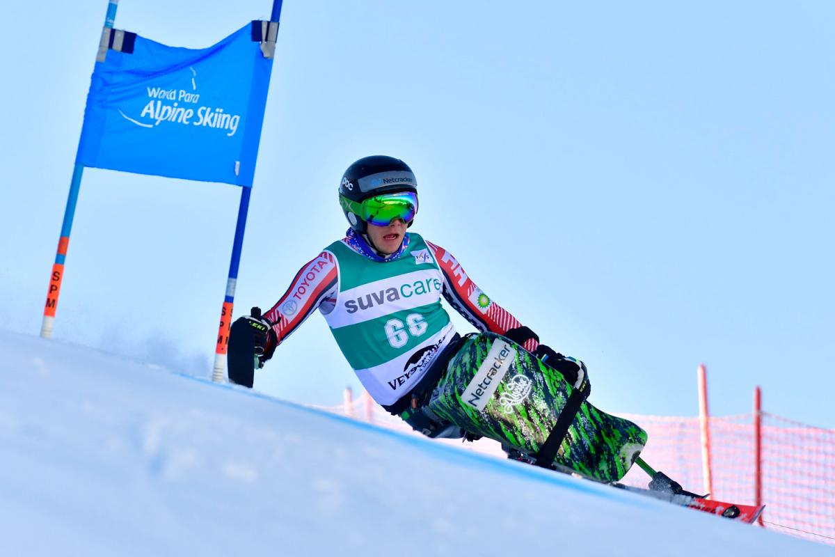 A male sit-skier competing in a Para alpine skiing giant slalom race