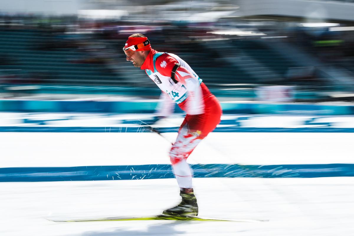 A men skiing in a cross-country competition in the snow with a blurred background 