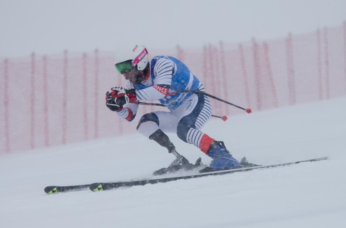 A men with a prosthetic leg skiing under heavy snow