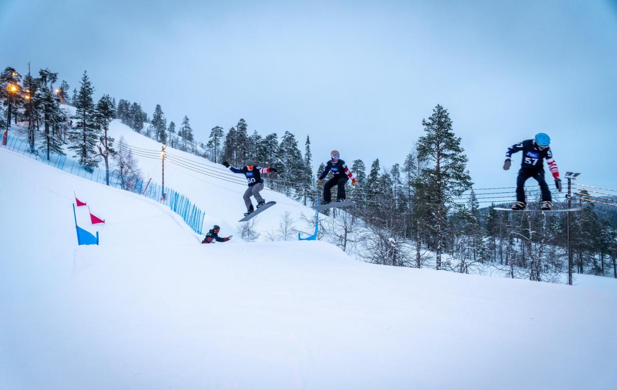 A group of male snowboarders jumping during a competition