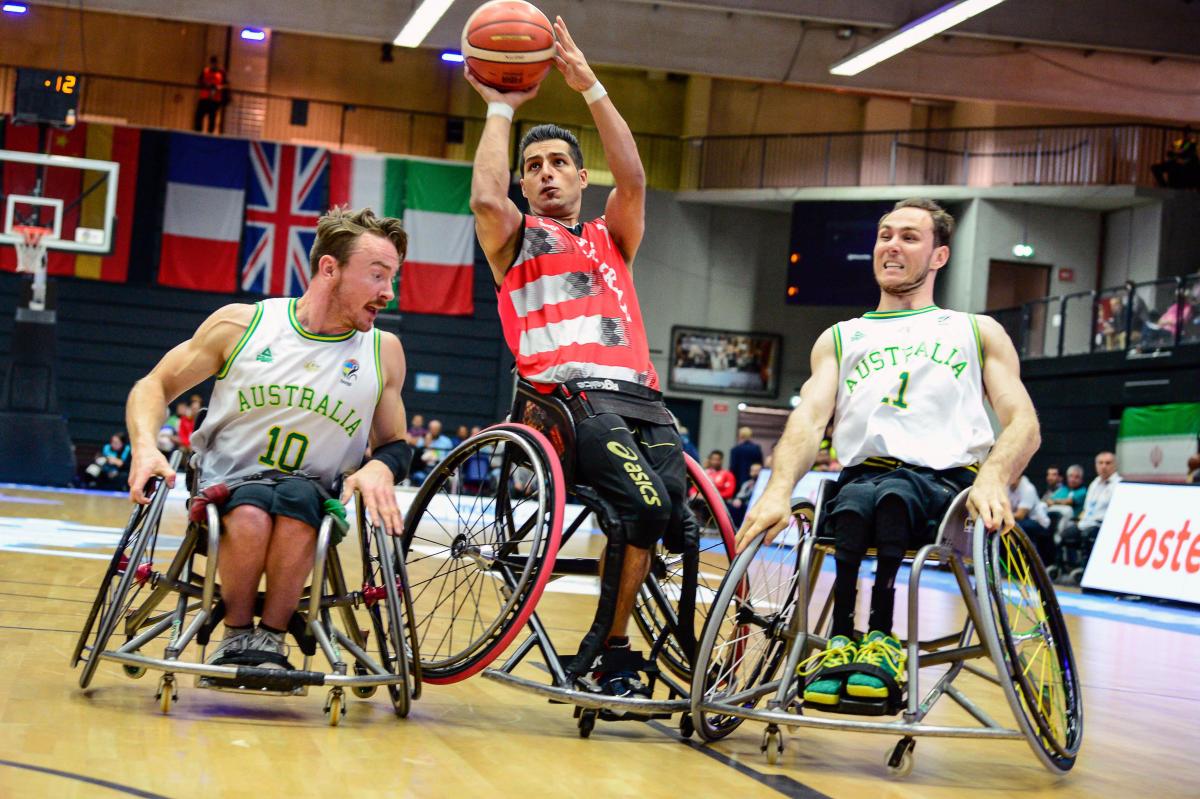 Two Australian men's wheelchair basketball players defend and Iranian athlete shooting the ball