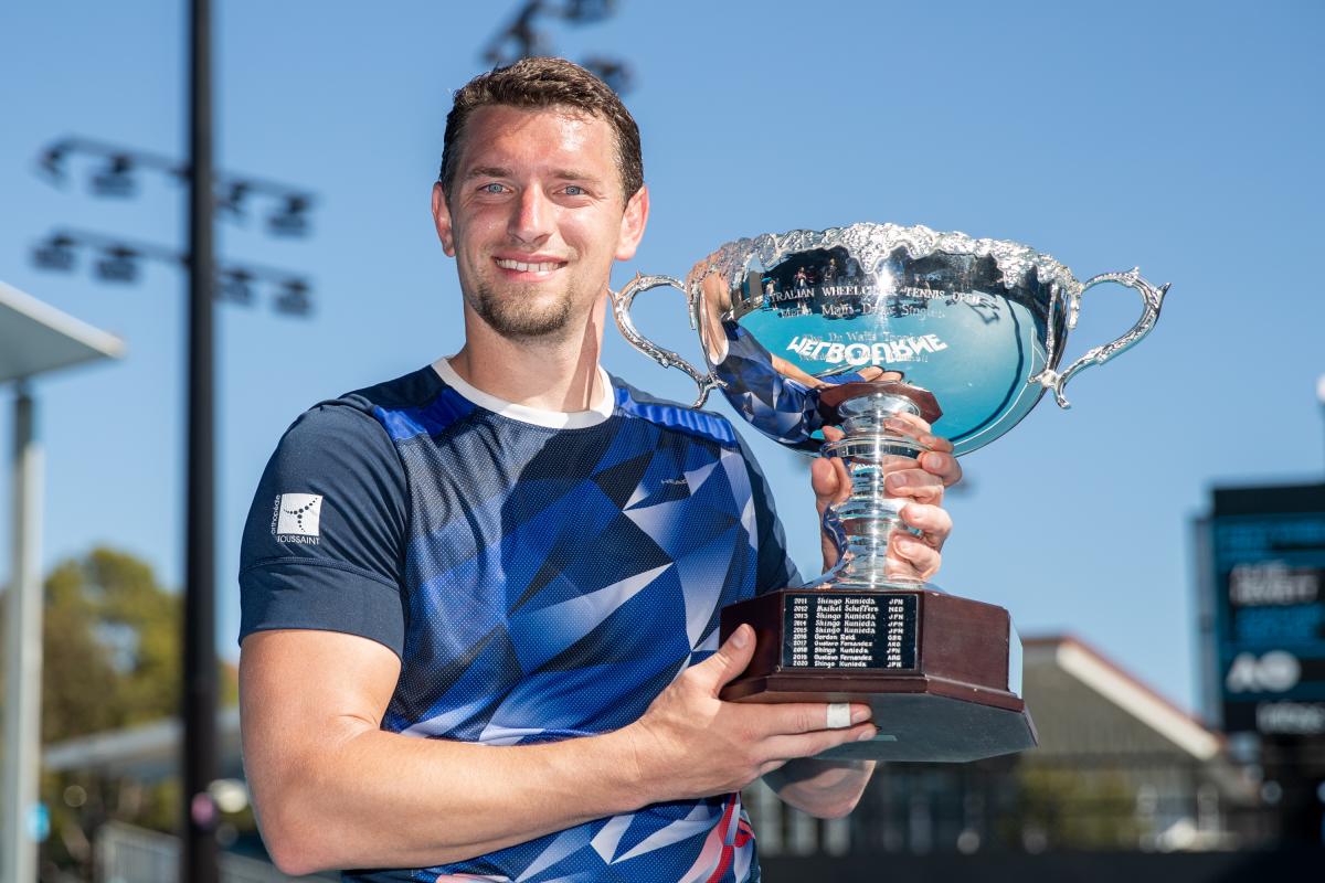 Belgian wheelchair tennis player smiles with Australian Open trophy