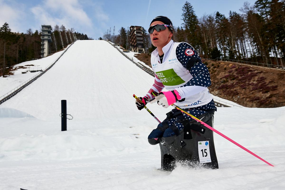 A female cross-country skier passing in front of a ski slope