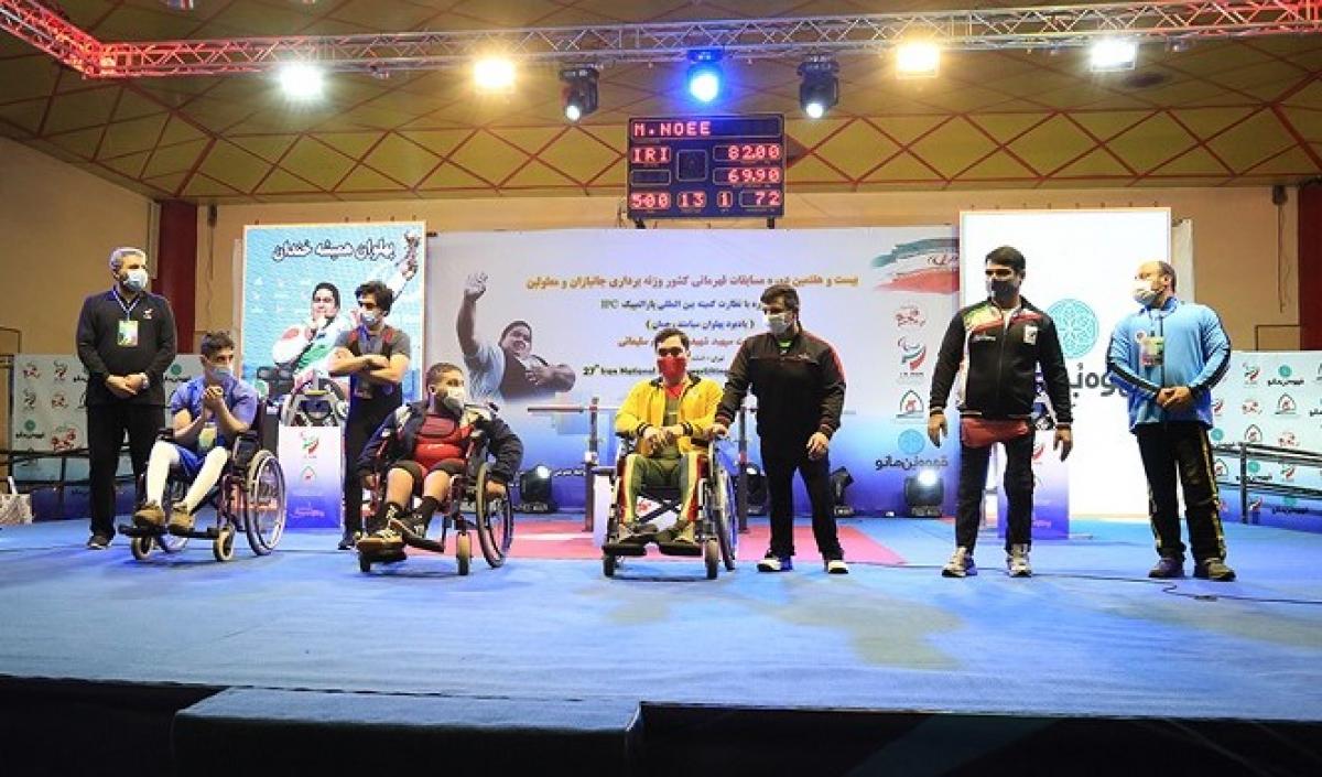 A group of three men in wheelchairs and five standing men on a stage