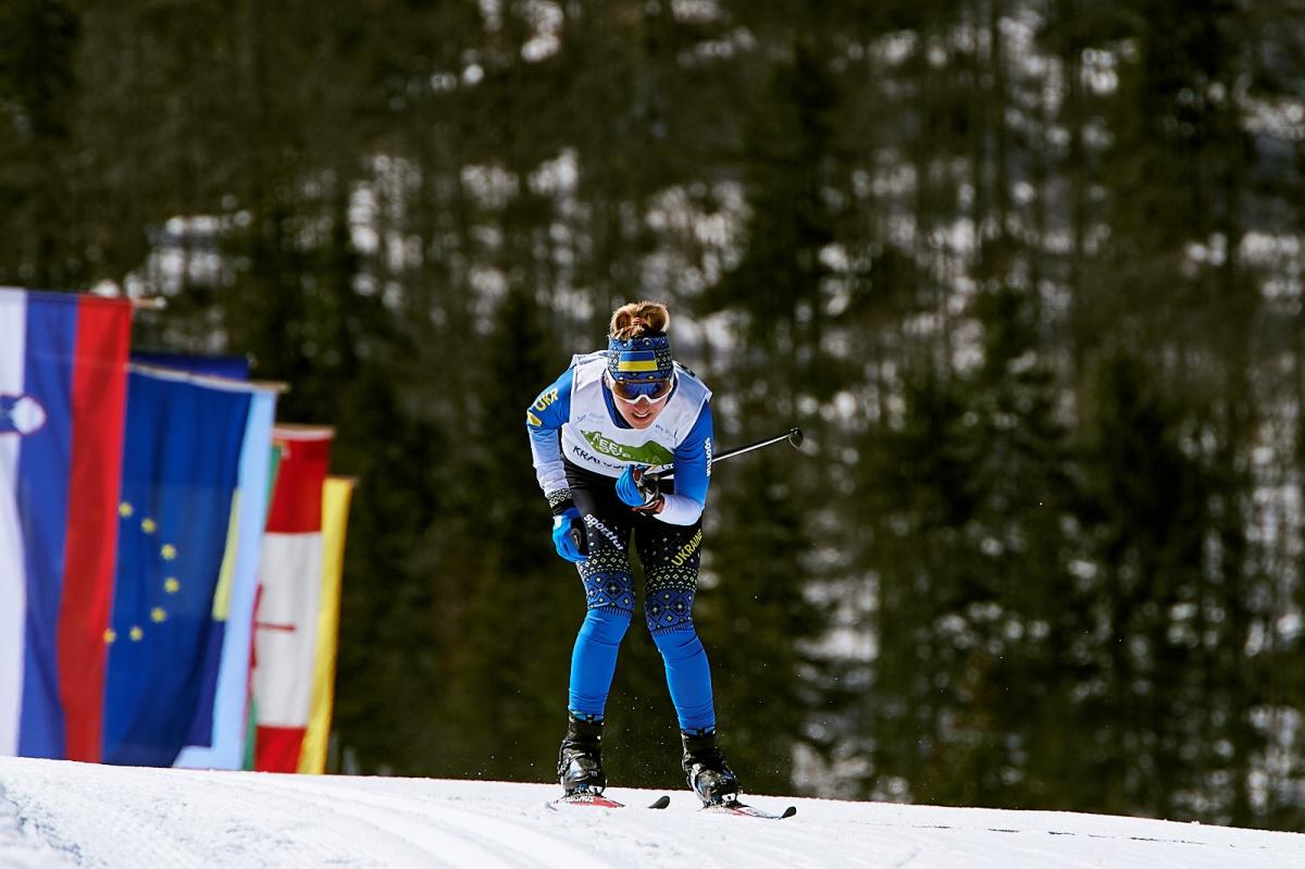 A female cross-country standing skier with a bandana with the Ukrainian flag competing in the snow