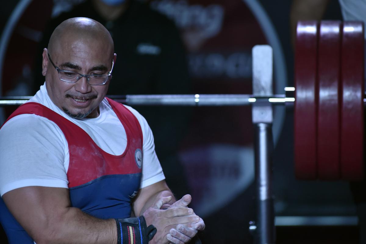 A man holding his hands on a bench press during a powerlifting competition