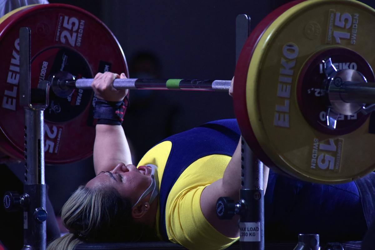 A woman lifting a bar on a bench press competition