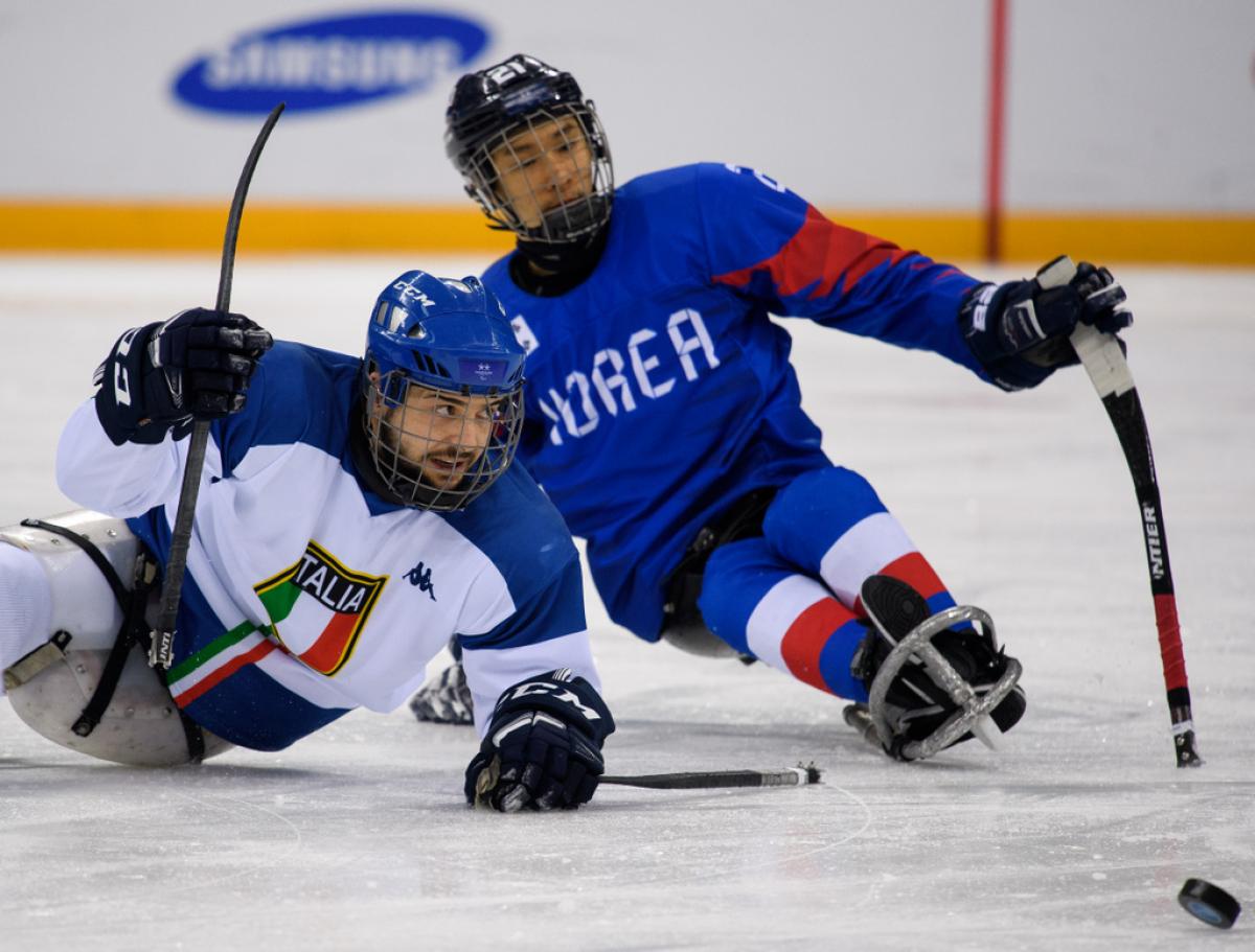 An Italian and a South Korea Para ice hockey player during a game on ice