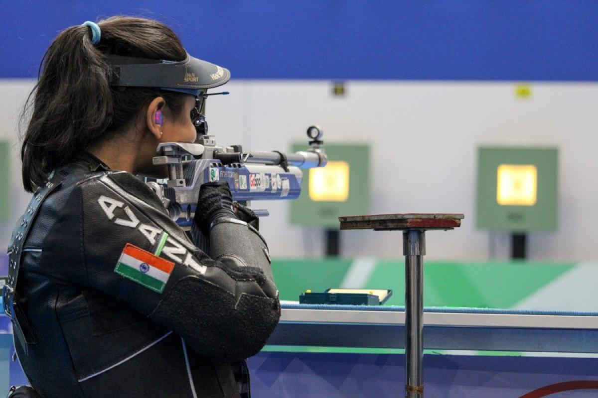 A woman shooting with a rifle in a shooting range seen from behind